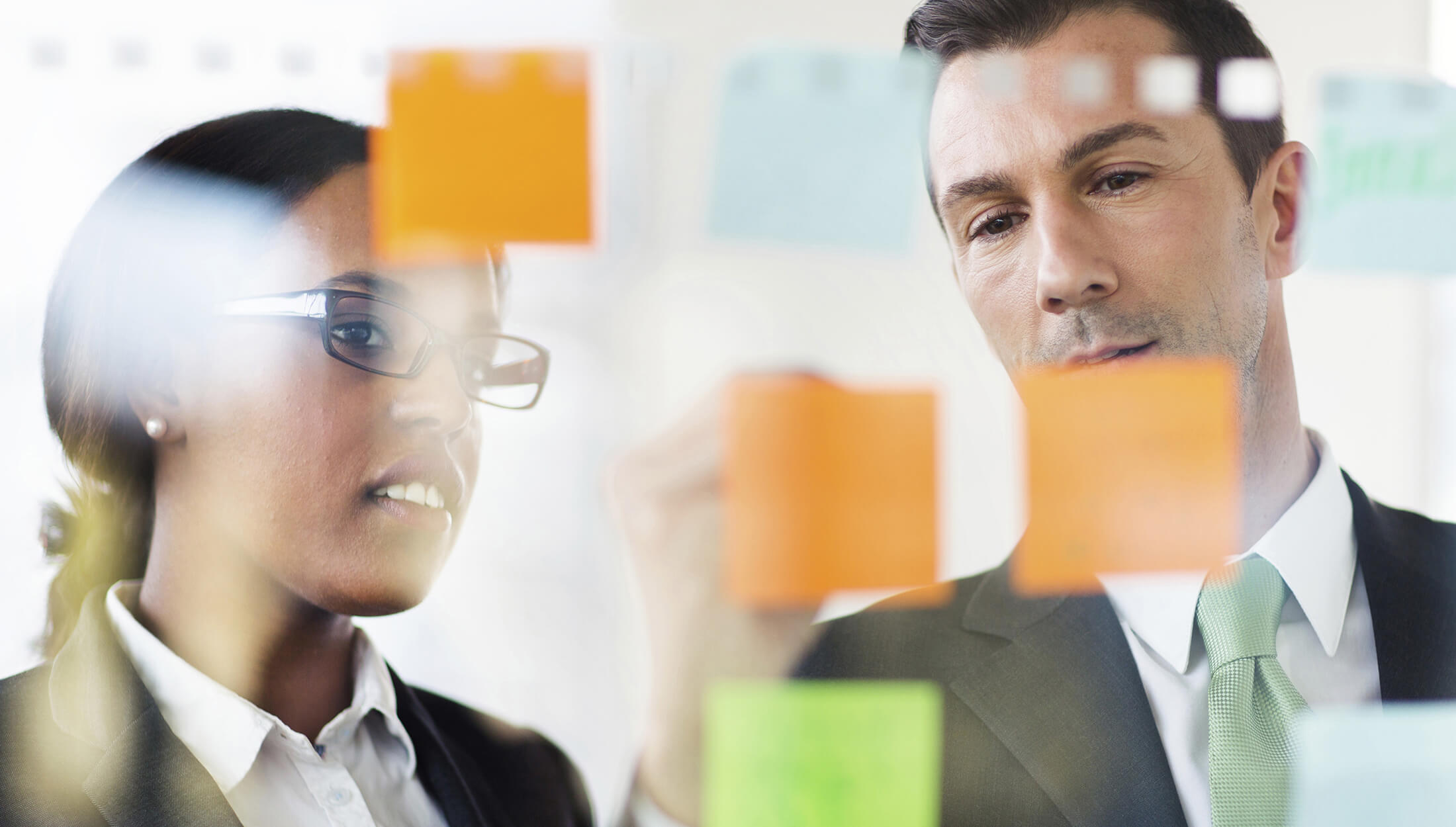 Man And A Wonal Looking At A Board With Sticky Notes