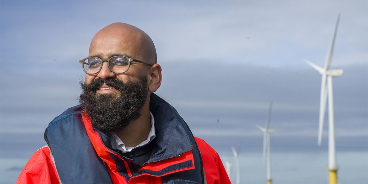 Man op zee met op de achtergrond wind turbines