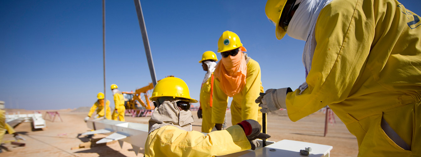 Workers wearing PPE constructing rig in desert